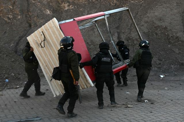 Riot police officers clear debris from a road during clashes with rural protesters in Lipari, La Paz department, Bolivia, on May 16, 2026. Bolivia's government reached an agreement on May 15 with thousands of miners who clashed with police in a protest that paralysed downtown La Paz. However, other sectors continue to block access routes to the city, home to the executive branch and Congress. (Photo by AIZAR RALDES / AFP)