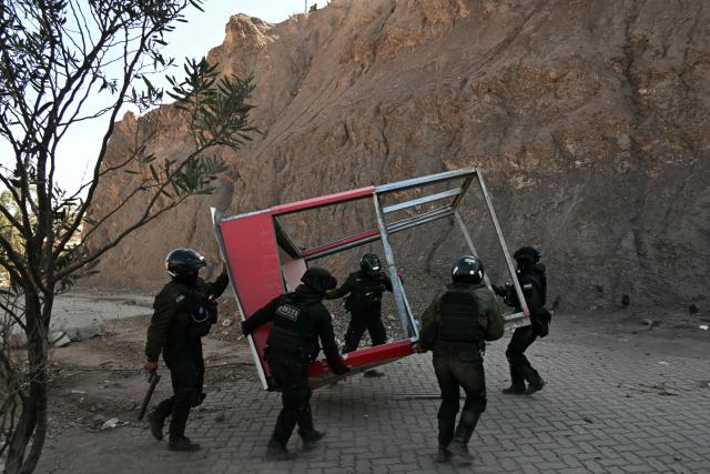 Riot police officers clear debris from a road during clashes with rural protesters in Lipari, La Paz department, Bolivia, on May 16, 2026. Bolivia's government reached an agreement on May 15 with thousands of miners who clashed with police in a protest that paralysed downtown La Paz. However, other sectors continue to block access routes to the city, home to the executive branch and Congress. (Photo by AIZAR RALDES / AFP)