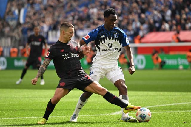 Bayer Leverkusen's Spanish defender #20 Alejandro Grimaldo and Hamburg's Belgian-Congolese midfielder #06 Albert Sambi Lokonga vie for the ball during the German first division Bundesliga football match between Bayer Leverkusen and Hamburger SV (HSV) in Leverkusen, western Germany, on May 16, 2026. (Photo by INA FASSBENDER / AFP) / DFL REGULATIONS PROHIBIT ANY USE OF PHOTOGRAPHS AS IMAGE SEQUENCES AND/OR QUASI-VIDEO