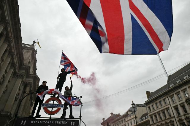 On Whitehall, supporters of British far-right activist Tommy Robinson, real name Stephen Yaxley-Lennon, wave Union flags as a march organised by Unite The Kingdom passes by in central London on May 16, 2026. (Photo by JUSTIN TALLIS / AFP)