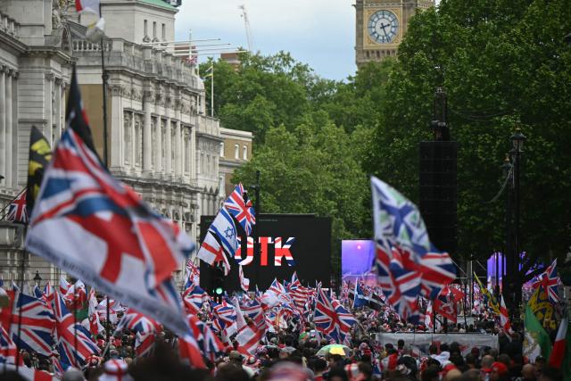 Supporters of British far-right activist Tommy Robinson, real name Stephen Yaxley-Lennon, wave flags as they take part in a march organised by Unite The Kingdom, in central London on May 16, 2026. (Photo by JUSTIN TALLIS / AFP)