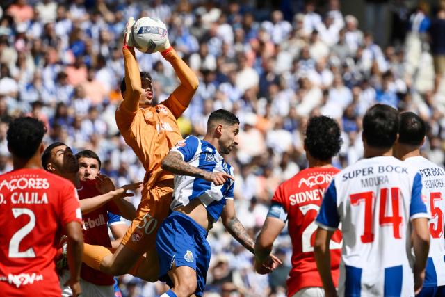 Santa Clara's Portuguese goalkeeper #50 Joao Afonso jumps to make a save against FC Porto's Argentine midfielder #22 Alan Varela during the Portuguese League football match between FC Porto and CD Santa Clara at the Dragao stadium in Porto on May 16, 2026. (Photo by Miguel RIOPA / AFP)
