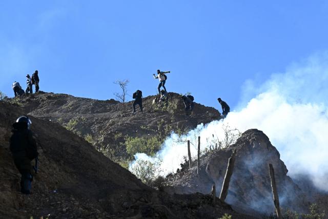 A rural protester throws stones from a hillside during clashes with riot police in Lipari, La Paz department, Bolivia, on May 16, 2026. Bolivia's government reached an agreement on May 15 with thousands of miners who clashed with police in a protest that paralysed downtown La Paz. However, other sectors continue to block access routes to the city, home to the executive branch and Congress. (Photo by AIZAR RALDES / AFP)