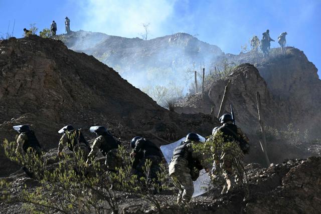 Riot police officers advance along a hillside amid tear gas during clashes with rural protesters in Lipari, La Paz department, Bolivia, on May 16, 2026. Bolivia's government reached an agreement on May 15 with thousands of miners who clashed with police in a protest that paralysed downtown La Paz. However, other sectors continue to block access routes to the city, home to the executive branch and Congress. (Photo by AIZAR RALDES / AFP)
