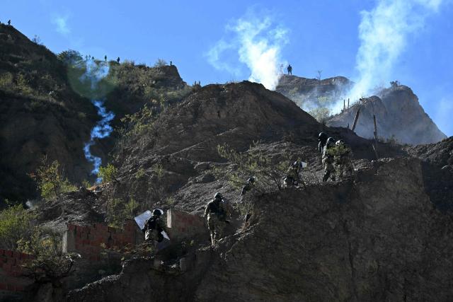 Riot police officers advance along a hillside amid tear gas during clashes with rural protesters in Lipari, La Paz department, Bolivia, on May 16, 2026. Bolivia's government reached an agreement on May 15 with thousands of miners who clashed with police in a protest that paralysed downtown La Paz. However, other sectors continue to block access routes to the city, home to the executive branch and Congress. (Photo by AIZAR RALDES / AFP)