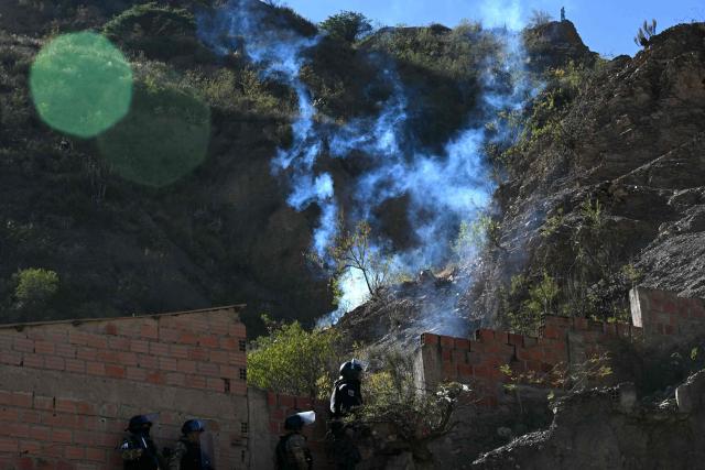 Riot police officers advance along a hillside amid tear gas during clashes with rural protesters in Lipari, La Paz department, Bolivia, on May 16, 2026. Bolivia's government reached an agreement on May 15 with thousands of miners who clashed with police in a protest that paralysed downtown La Paz. However, other sectors continue to block access routes to the city, home to the executive branch and Congress. (Photo by AIZAR RALDES / AFP)