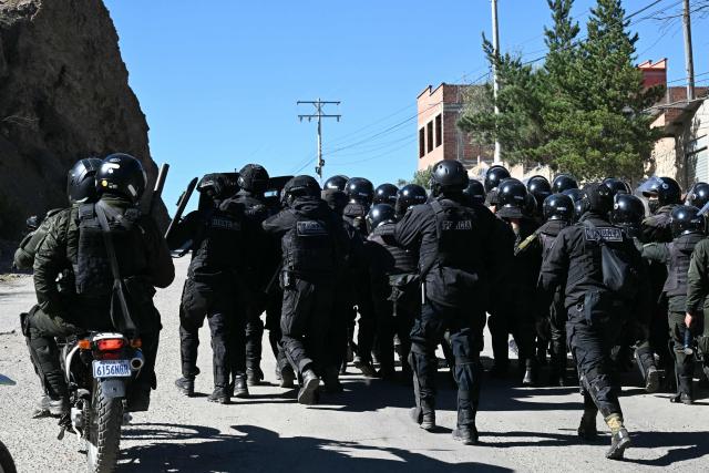 Riot police officers patrol a road during clashes with rural protesters blocking the route in Lipari, La Paz department, Bolivia, on May 16, 2026. Bolivia's government reached an agreement on May 15 with thousands of miners who clashed with police in a protest that paralysed downtown La Paz. However, other sectors continue to block access routes to the city, home to the executive branch and Congress. (Photo by AIZAR RALDES / AFP)