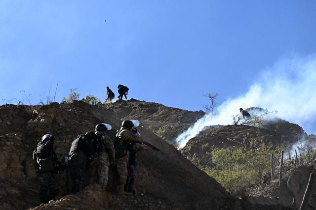 Riot police officers advance along a hillside amid tear gas during clashes with rural protesters in Lipari, La Paz department, Bolivia, on May 16, 2026. Bolivia's government reached an agreement on May 15 with thousands of miners who clashed with police in a protest that paralysed downtown La Paz. However, other sectors continue to block access routes to the city, home to the executive branch and Congress. (Photo by AIZAR RALDES / AFP)