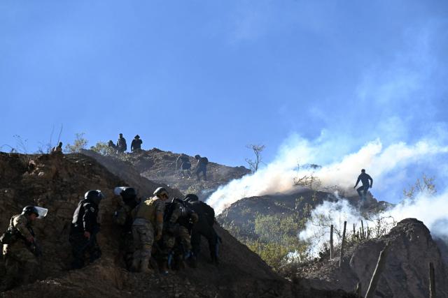 Riot police officers advance along a hillside amid tear gas during clashes with rural protesters in Lipari, La Paz department, Bolivia, on May 16, 2026. Bolivia's government reached an agreement on May 15 with thousands of miners who clashed with police in a protest that paralysed downtown La Paz. However, other sectors continue to block access routes to the city, home to the executive branch and Congress. (Photo by AIZAR RALDES / AFP)