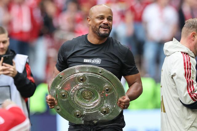 Bayern Munich's Belgian head coach Vincent Kompany walks with the trophy in his hands after a beer shower during celebrations after the German first division Bundesliga football match between FC Bayern Munich and FC Cologne in Munich, southern Germany, on May 16, 2026. (Photo by Alexandra BEIER / AFP) / DFL REGULATIONS PROHIBIT ANY USE OF PHOTOGRAPHS AS IMAGE SEQUENCES AND/OR QUASI-VIDEO