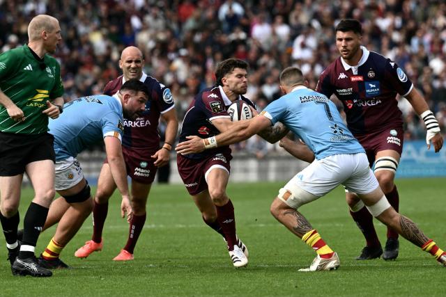 France's fly-half Matthieu Jalibert (C) is tackled by Perpignan's French flanker Max Hicks (2R) as he runs with the ball during the French Top 14 rugby union match between Union Bordeaux-Begles (UBB) and USAP Perpignan at the Chaban-Delmas Stadium in Bordeaux, south-western France on May 16, 2026. (Photo by Philippe LOPEZ / AFP)