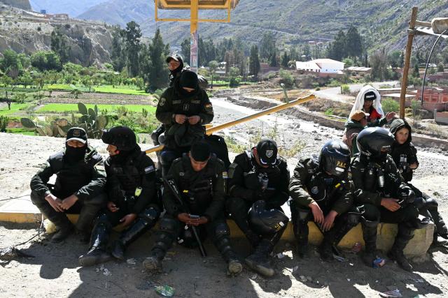 Riot police officers rest after retreating to a safer position during clashes with rural protesters near Lipari, La Paz department, Bolivia, on May 16, 2026. Bolivia's government reached an agreement on May 15 with thousands of miners who clashed with police in a protest that paralysed downtown La Paz. However, other sectors continue to block access routes to the city, home to the executive branch and Congress. (Photo by AIZAR RALDES / AFP)