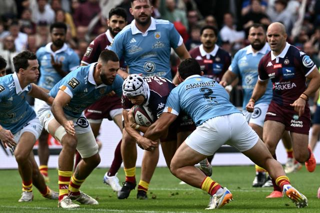 Bordeaux-Begles' French full-back Louis Bielle-Biarrey (C) is tackled by Perpignan's Argentine hooker Ignacio Ruiz (CR) as he runs with the ball during the French Top 14 rugby union match between Union Bordeaux-Begles (UBB) and USAP Perpignan at the Chaban-Delmas Stadium in Bordeaux, south-western France on May 16, 2026. (Photo by Philippe LOPEZ / AFP)