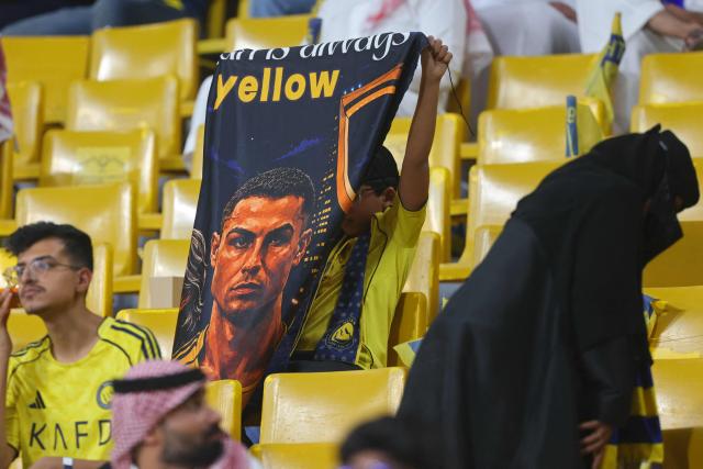 A fan holds a banner with picture of Nassr's Portuguese forward #07 Cristiano Ronaldo before the start of the 2026 AFC Champions League Two final football match between Al-Nassr and Gamba Osaka at the Al-Awwal Park Stadium in Riyadh on May 16, 2026. (Photo by Fayez NURELDINE / AFP)