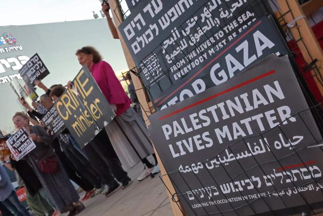 Israeli left-wing activists hold placards during a demonstration against the country's ruling government and the ongoing war in the Middle East at the HaBima Square in Tel Aviv on May 16, 2026. (Photo by Jack GUEZ / AFP)