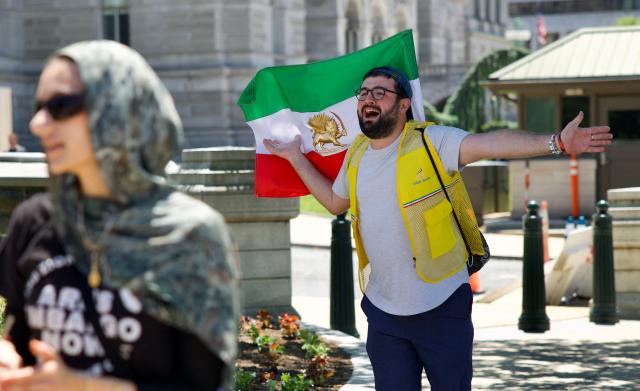 A man waving an Iranian pre-Islamic revolution of 1979 flag gestures as demonstrators gather near the US Capitol while participating in a Nakba solidarity bike ride from Dupont Circle to the US Capitol in Washington, DC, on May 16, 2026, marking the 78th anniversary of the Nakba. (Photo by Amid FARAHI / AFP)