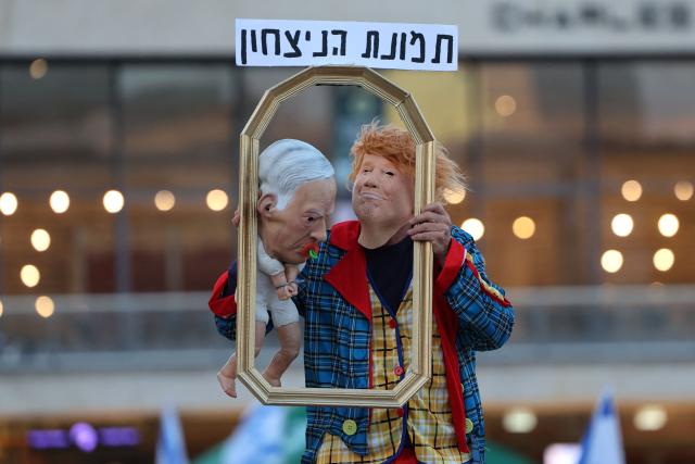 An Israeli left-wing activist in costume with a mask depicting US President Donald Trump holds a baby puppet depicting Israel's Prime Minister Benjamin Netanyahu during a demonstration against the country's ruling government and the ongoing war in the Middle East at the HaBima Square in Tel Aviv on May 16, 2026. (Photo by Jack GUEZ / AFP) / 