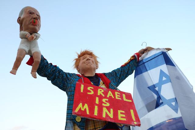 An Israeli left-wing activist in costume with a mask depicting US President Donald Trump holds a baby puppet depicting Israel's Prime Minister Benjamin Netanyahu during a demonstration against the country's ruling government and the ongoing war in the Middle East at the HaBima Square in Tel Aviv on May 16, 2026. (Photo by Jack GUEZ / AFP) / 