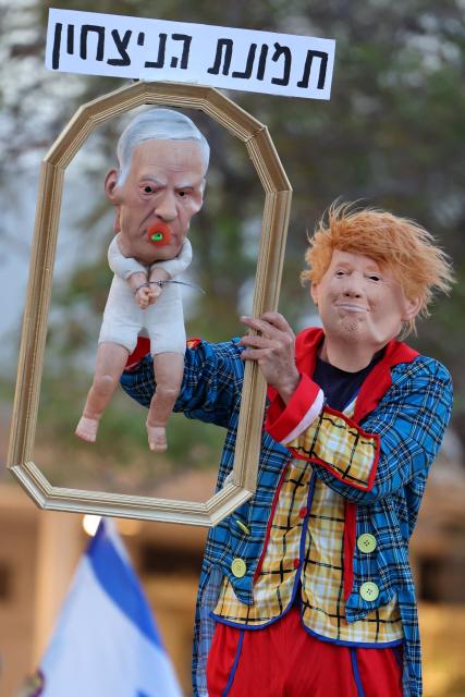 An Israeli left-wing activist in costume with a mask depicting US President Donald Trump holds a baby puppet depicting Israel's Prime Minister Benjamin Netanyahu during a demonstration against the country's ruling government and the ongoing war in the Middle East at the HaBima Square in Tel Aviv on May 16, 2026. (Photo by Jack GUEZ / AFP) / 