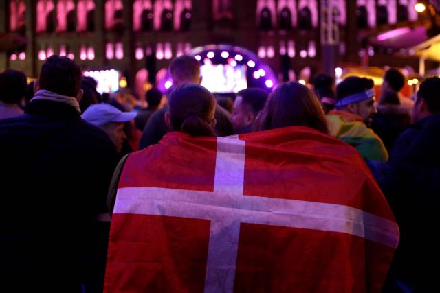 Fans of Denmark huddle with a national flag as spectators gather at the fan area to watch the final of the Eurovision Song Contest 2026 (ESC) outside the City Hall in Vienna, Austria on May 16, 2026. (Photo by Alex HALADA / AFP)