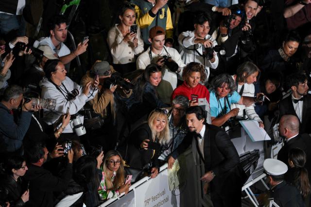 US actor Adam Driver takes selfies with fans as he arrives for the screening of the film "Paper Tiger" at the 79th edition of the Cannes Film Festival in Cannes, southern France on May 16, 2026. (Photo by Olivier CHASSIGNOLE / AFP)