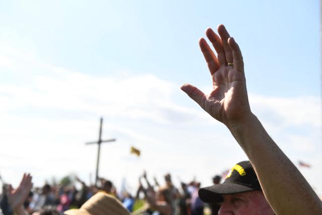 Christian worshipers raise their hands as faith leaders pray during the Roots of Revival event at the Washington Monument, held a day ahead of "Rededicate 250: A National Jubilee of Prayer, Praise and Thanksgiving" in Washington, DC, on May 16, 2026. (Photo by Matthew Hatcher / AFP)