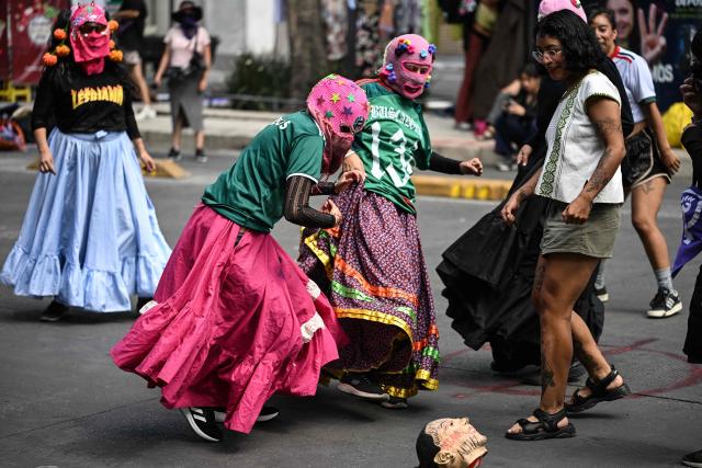 Activists from a feminist collective protesting against the upcoming FIFA World Cup play soccer with a ball covered by a mask depicting Mexico's President Claudia Sheinbaum in Mexico City on May 16, 2026. (Photo by Yuri CORTEZ / AFP)