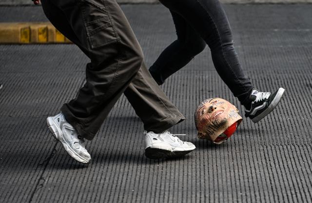 Activists from a feminist collective protesting against the upcoming FIFA World Cup play soccer with a ball covered by a mask depicting Mexico's President Claudia Sheinbaum in Mexico City on May 16, 2026. (Photo by Yuri CORTEZ / AFP)