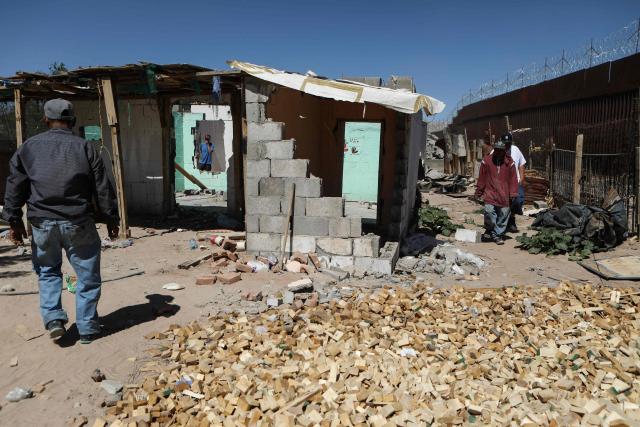 People walk among houses being demolished by municipal workers at the Mexico-US border wall in Puerto Anapra neighborhood, Ciudad Juarez, Chihuahua state, Mexico on May 16, 2026. (Photo by Herika Martinez / AFP)
