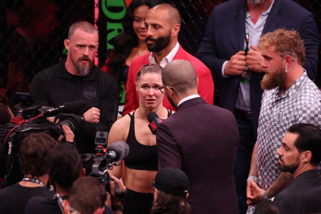 US Mixed Martial Arts (MMA) fighter Ronda Rousey is interviewed, flanked by US boxer and influencer Jake Paul (R), after defeating Gina Carano during their Featherweight Bout at the Intuit Dome in Inglewood, California, on May 16, 2026. (Photo by Patrick T. Fallon / AFP)