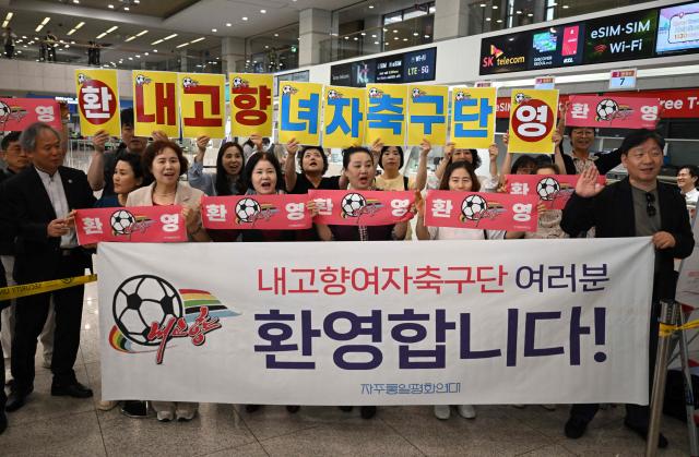 South Korean activists hold banners welcoming North Korea's Naegohyang Women's FC as they wait for the North Korean team's arrival at Incheon International Airport in Incheon on May 17, 2026, ahead of the Women's Asian Champions League semifinal match between South Korea's Suwon FC Women and North Korea's Naegohyang Women's FC. (Photo by Jung Yeon-je / AFP)