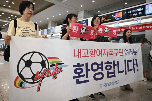 South Korean activists hold banners welcoming North Korea's Naegohyang Women's FC as they wait for the North Korean team's arrival at Incheon International Airport in Incheon on May 17, 2026, ahead of the Women's Asian Champions League semifinal match between South Korea's Suwon FC Women and North Korea's Naegohyang Women's FC. (Photo by Jung Yeon-je / AFP)
