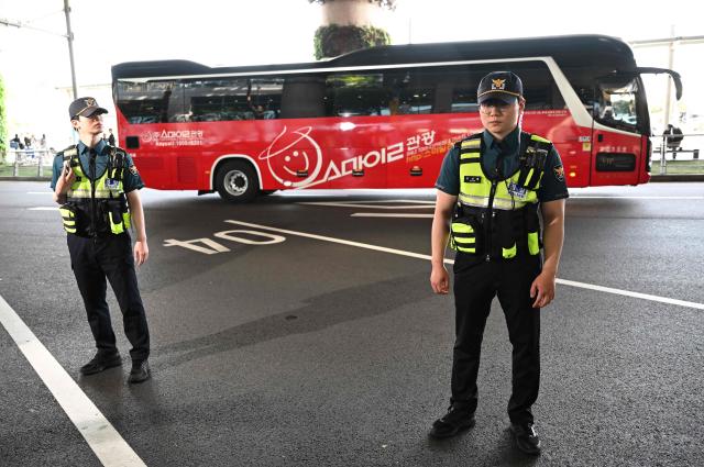 Police officers stand guard as a bus carrying North Korea's Naegohyang Women's FC players leaves at Incheon International Airport in Incheon on May 17, 2026, ahead of the Women's Asian Champions League semi-final football match against South Korea's Suwon FC Women. A North Korean women's football team arrived in South Korea on May 17, marking the first visit by a sports team from the isolated country to its southern neighbour in eight years, to play in the Asian Champions League semi-finals. (Photo by Jung Yeon-je / AFP)