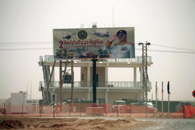A billboard showing an image of Libyan military strongman Khalifa Haftar is erected on top of a military building close to there the "Dara’ al-Karama 2" military exercises are taking place, in the Ras al-Alba region in southeastern Libya on May 16. 2026. The exercises involve extensive participation from various ground, air, and naval units, making them one of the largest military exercises the Libyan Army has conducted in recent years, with more than 25,000 military personnel taking part. (Photo by Abdullah DOMA / AFP)