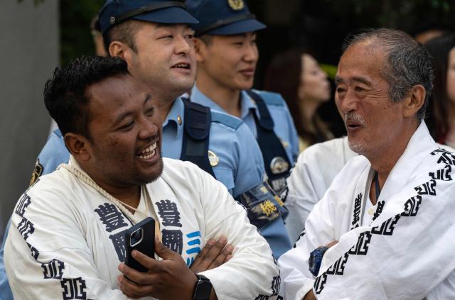 Participants laugh next to the police during final day of the Sanja Matsuri festival in Tokyo on May 17, 2026, one of Tokyo’s largest Shinto celebrations. (Photo by Andrew CABALLERO-REYNOLDS / AFP)