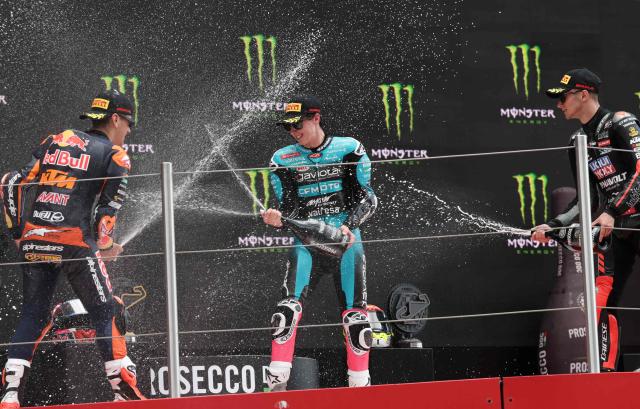 Riders (L-R) Team Red Bull KTM Ajo's Alvaro Carpe, seond placed,  Team CF Moto Aspar Racing Team's winner Maximo Quiles, and third placed  Team Liqui Moly Husqvarna Intact GP's David Munoz celebrate on the podium for the Moto3 race of the 2026 Catalunya Moto Grand Prix at the Catalunya racetrack in Montmelo, near Barcelona, on May 17, 2026. (Photo by Lluis GENE / AFP)