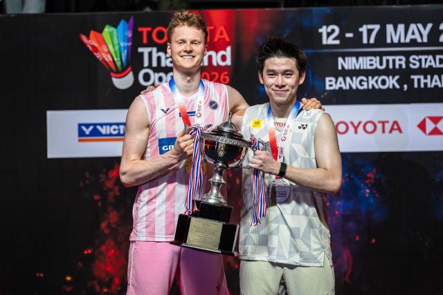 Denmark's Anders Antonsen (L) celebrates with the trophy next to runner-up Thailand's Kunlavut Vitidsarn following their men's singles final match at the Thailand Open badminton tournament in Bangkok on May 17, 2026. (Photo by chanakarn LAOSARAKHAM / AFP)