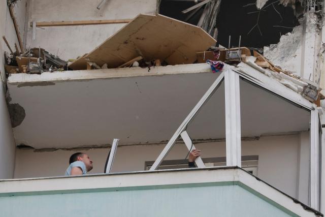 Local residents inspect a damaged balcony in a residential building following an air attack in Krasnogorsk, Moscow region on May 17, 2026, amid the ongoing Russian-Ukrainian conflict. A wave of almost 600 Ukrainian drones attacked Russia overnight killing four people, authorities said on May 17, 2026, as Ukraine's President Volodymyr Zelensky called the barrage an 'entirely justified' retribution for Moscow's own pummelling of Ukraine. (Photo by TATYANA MAKEYEVA / AFP)