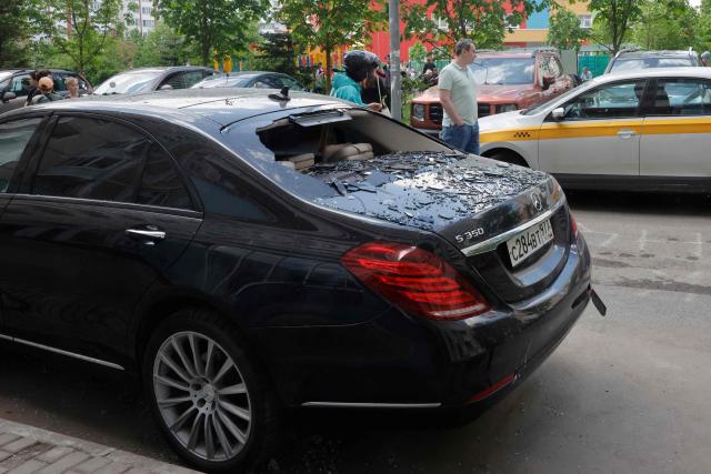 Local residents stand next to a damaged car in the courtyard of a residential building following an air attack in Krasnogorsk, Moscow region on May 17, 2026, amid the ongoing Russian-Ukrainian conflict. A wave of almost 600 Ukrainian drones attacked Russia overnight killing four people, authorities said on May 17, 2026, as Ukraine's President Volodymyr Zelensky called the barrage an 'entirely justified' retribution for Moscow's own pummelling of Ukraine. (Photo by TATYANA MAKEYEVA / AFP)