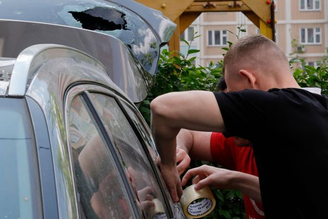 Local residents make a temporary repair on a damaged car in the courtyard of a residential building following an air attack in Krasnogorsk, Moscow region on May 17, 2026, amid the ongoing Russian-Ukrainian conflict. A wave of almost 600 Ukrainian drones attacked Russia overnight killing four people, authorities said on May 17, 2026, as Ukraine's President Volodymyr Zelensky called the barrage an 'entirely justified' retribution for Moscow's own pummelling of Ukraine. (Photo by TATYANA MAKEYEVA / AFP)
