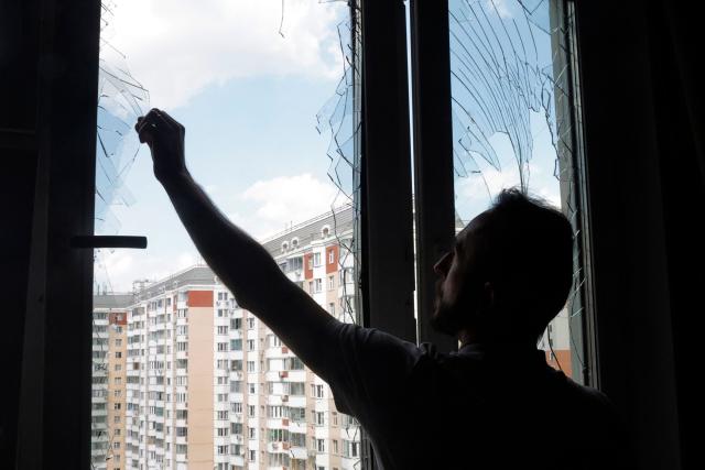 A local resident removes glass shards from a broken window in a residential building following an air attack in Krasnogorsk, Moscow region on May 17, 2026, amid the ongoing Russian-Ukrainian conflict. A wave of almost 600 Ukrainian drones attacked Russia overnight killing four people, authorities said on May 17, 2026, as Ukraine's President Volodymyr Zelensky called the barrage an 'entirely justified' retribution for Moscow's own pummelling of Ukraine. (Photo by TATYANA MAKEYEVA / AFP)