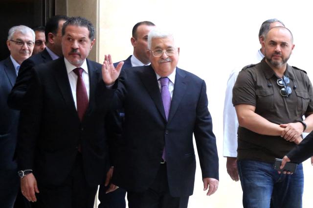 (FILES) Palestinian president Mahmud Abbas (C) accompanied by his two sons, to his left Yasser and to his right Tarek, waves as he leaves a hospital near Ramallah in the occupied West Bank on May 28, 2018 following eight days of treatment for pneumonia. The son of Palestinian president Mahmoud Abbas won a seat on Fatah's top decision-making body on May 17, 2026, as initial results emerged from the Palestinian movement's first congress in a decade. Yasser Abbas, 64, a businessman who spends most of his time in Canada, secured a place on the central committee after being appointed around five years ago as his father's "special representative"  a role that marked his emergence. (Photo by ABBAS MOMANI / AFP)
