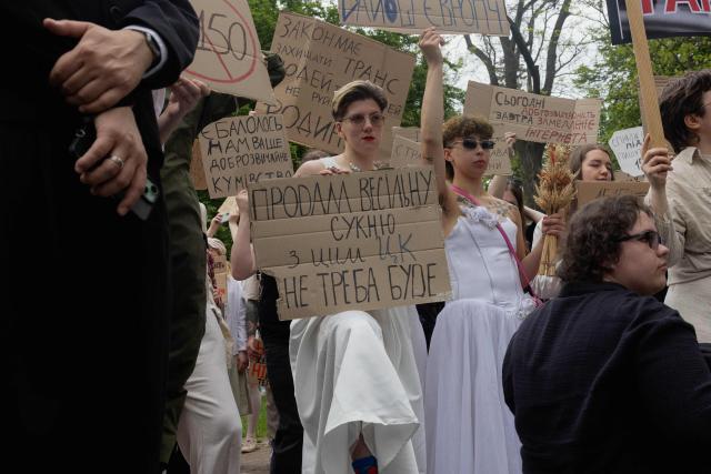 Protesters dressed as brides hold placards during a demonstration against the new Civil Code, warning it could restrict the rights of women, children, people with disabilities, and the LGBTQ community by regulating issues such as abortion, early marriage, and alimony in Kyiv on May 17, 2026, amid the Russian invasion of Ukraine. (Photo by Tetiana DZHAFAROVA / AFP)