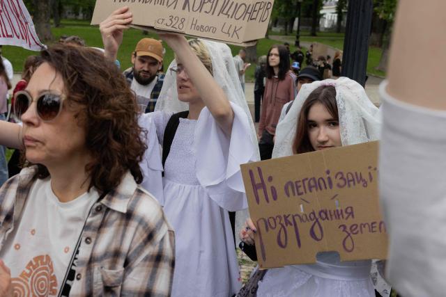 Protesters dressed as brides hold placards during a demonstration against the new Civil Code, warning it could restrict the rights of women, children, people with disabilities, and the LGBTQ community by regulating issues such as abortion, early marriage, and alimony in Kyiv on May 17, 2026, amid the Russian invasion of Ukraine. (Photo by Tetiana DZHAFAROVA / AFP)