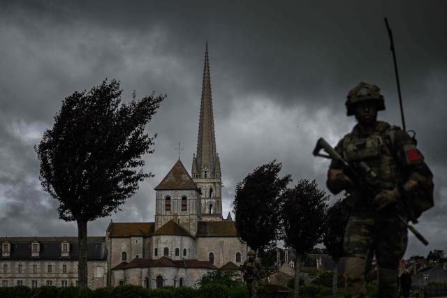 French Foreign Legion paratroopers from the 2nd Foreign Parachute Regiment (2e REP) patrol a road beside the UNESCO-listed abbey of Saint-Savin-sur-Gartempe during a bridge defence exercise in Saint-Savin, south-western France, on May 17, 2026. The exercise, running from May 11 to 20 across Nouvelle-Aquitaine and Centre-Val de Loire, tests short-notice redeployment and interoperability between air and ground components  capabilities central to France's contribution to NATO rapid-reaction forces. (Photo by Philippe LOPEZ / AFP)