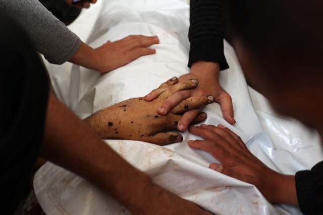 EDITORS NOTE: Graphic content / Relatives place their hands over the body of Ibrahim Rayyan, a Palestinian man who was reportedly killed in an Israeli strike, inside the morgue of Al-Aqsa hospital in Deir al-Balah, central Gaza Strip on May 17, 2026. Prime Minister Benjamin Netanyahu said on May 17 that Israel had almost completed a key goal of the war in Gaza -- eliminating all those responsible for orchestrating the October 7 attacks. (Photo by Eyad Baba / AFP)