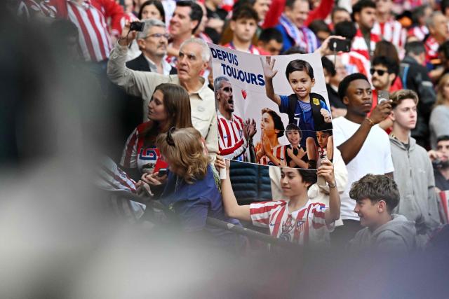 An Atletico de Madrid fan holds a banner featuring a photo of French forward Antoine Griezmann and a message reading in French 'Since Always' before the Spanish league football match between Club Atletico de Madrid and Girona FC at the Metroplitano stadium in Madrid on May 17, 2026. French forward Antoine Griezmann received a warm goodbye from the club's supporters today. Atletico's all-time top goalscorer will head to the United States to play for MLS side Orlando City. (Photo by Javier SORIANO / AFP)