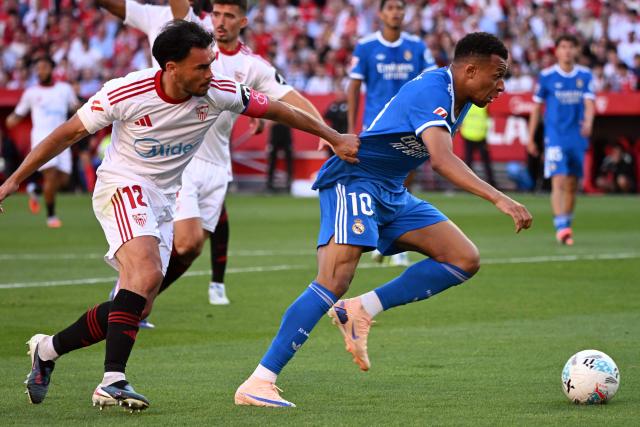 Sevilla's Chilean defender #12 Gabriel Suazo grabs Real Madrid's French forward #10 Kylian Mbappe's jersey during the Spanish league football match between Sevilla FC and Real Madrid CF at the Sanchez Pizjuan stadium in Seville on May 17, 2026. (Photo by CRISTINA QUICLER / AFP)