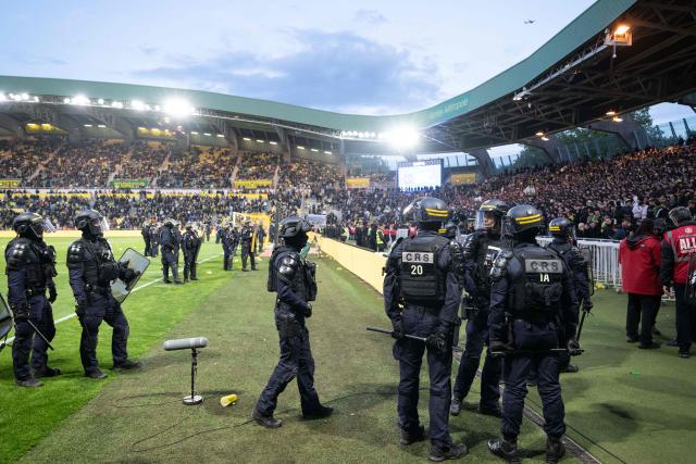 Anti-riot police officers secure the pitch after Nantes' supporters threw smoke flares and invaded it during the French L1 football match between FC Nantes and Toulouse FC at the Stade de la Beaujoire–Louis Fonteneau in Nantes, western France, on May 17, 2026. (Photo by Sebastien Salom-Gomis / AFP)