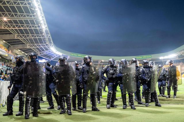 TOPSHOT - Anti-riot police officers secure the pitch after Nantes' supporters threw smoke flares and invaded it during the French L1 football match between FC Nantes and Toulouse FC at the Stade de la Beaujoire–Louis Fonteneau in Nantes, western France, on May 17, 2026. (Photo by Sebastien Salom-Gomis / AFP)
